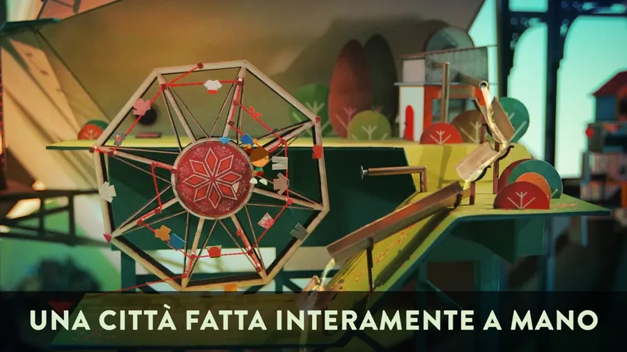 Una ruota panoramica di carta e una piccola città di cartone con alberi stilizzati, illuminata da una luce calda: una scena del gioco Lumino City.